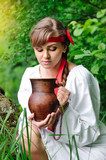 Beautiful young girl with a ceramic jug at the well  Folklor Fototapeta