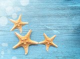 Three starfish on a blue wooden background Styl Marynistyczny Fototapeta