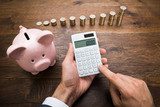 Businessman With Coins And Piggybank Using Calculator Plakaty do Biura Plakat