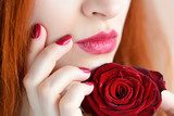 Portrait with red rose flower. Dark red lips and nails. Beautiful red-haired young woman. Obrazy do Salonu Kosmetycznego Obraz