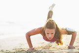 Female athlete doing push ups on beach  Fototapety do Klubu Fitness Fototapeta