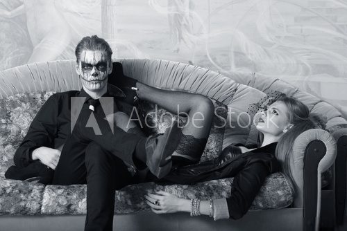 young man and woman on the sofa. makeup in Halloween theme  Czarno Białe Obraz