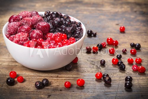 frozen berries in plate on wooden background  Obrazy do Kuchni  Obraz