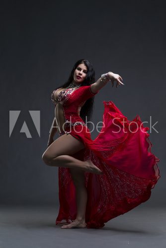 Young beautiful exotic eastern women performs belly dance in ethnic red dress on gray background Fototapety do Szkoły Tańca Fototapeta