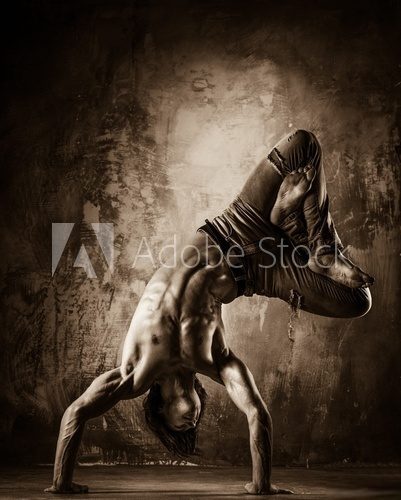 Young man with naked torso doing acrobatic movements  Fototapety Sepia Fototapeta