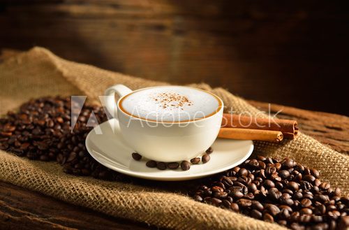 A cup of cappuccino and coffee beans on old wooden background  Fototapety do Kawiarni Fototapeta