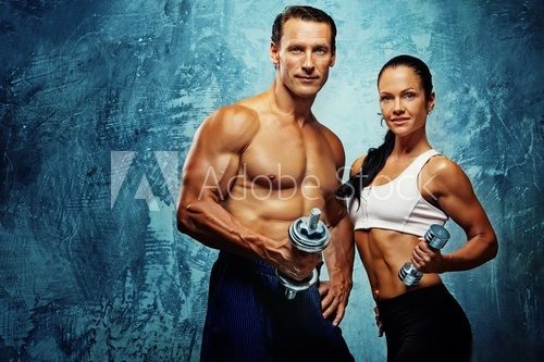 Athletic man and woman with a dumbells.  Fototapety do Siłowni Fototapeta