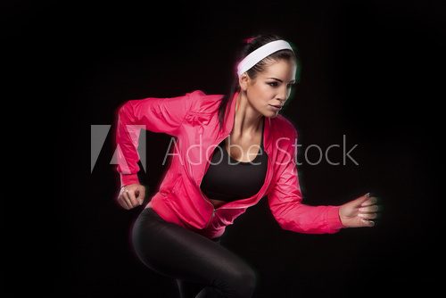 Beautiful young jogging woman. Isolated over black background (c  Fototapety do Klubu Fitness Fototapeta