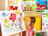 Child painting at easel.  Fototapety do Przedszkola Fototapeta