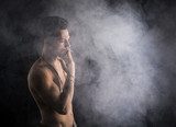 Shirtless young man smoking cigarette with a lot of smoke around  Ludzie Obraz