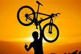cyclist raising his bike with thumbs up silhouette  Sport Fototapeta