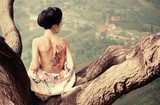 Woman with snake tattoo sitting on tree branch  Orientalne Fototapeta