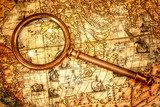 Vintage magnifying glass lies on an ancient world map  Mapa Świata Fototapeta