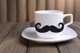 Cup with mustache on table on wooden background  Kawa Fototapeta