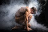Handsome Nude Muscle Man Crouching in Fog in Studio  Ludzie Plakat