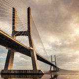 Vasco da Gama Bridge over the Tagus river at sunrise with cloudy  Architektura Plakat