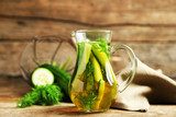 Glass ewer with fresh organic cucumber water on wooden table  Obrazy do Kuchni  Obraz