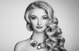 Black and white photo of beautiful woman with elegant hairstyle. Blonde girl with long wavy hair. Jewelry and make-up. Beauty style model Obrazy do Salonu Fryzjerskiego Obraz