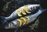 Sea bass fish with lemon on blackboard. Preparing for grill Obrazy do Jadalni Obraz