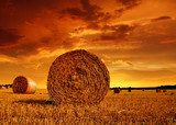 Straw bales on farmland with red cloudy sky  Zachód Słońca Fototapeta