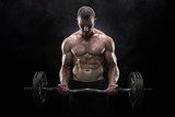 Young muscular man lifting weights over dark background  Fototapety do Siłowni Fototapeta
