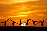 group of gymnasts tumbling in sunset  Sport Fototapeta
