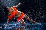 Woman dancing under rain in orange dress. Studio  Fototapety do Szkoły Tańca Fototapeta
