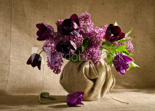 Beautiful bouquet of tulips with sprigs of lilac in a vase on a  Kwiaty Obraz
