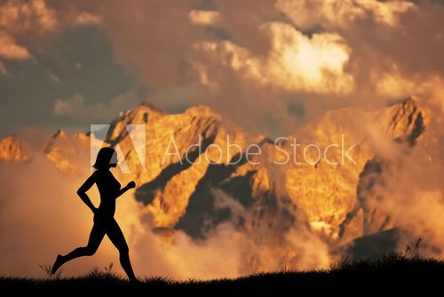 Silhouette of a woman running jogging in the mountains at sunset  Fototapety do Klubu Fitness Fototapeta