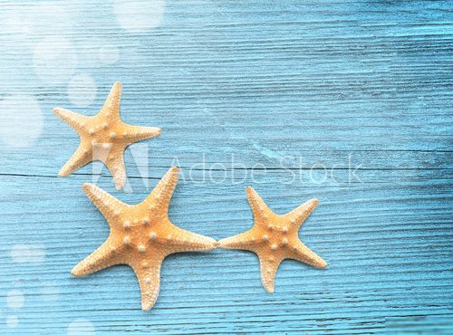 Three starfish on a blue wooden background Styl Marynistyczny Fototapeta