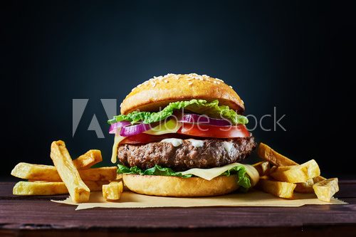 Craft beef burger and french fries on wooden table isolated on dark background. Obrazy do Jadalni Obraz