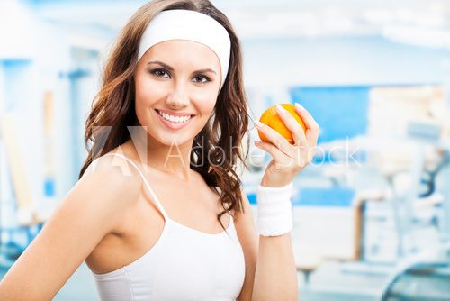 Woman with orange, at fitness center  Fototapety do Klubu Fitness Fototapeta