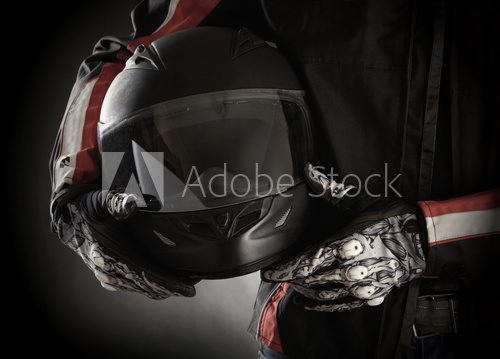 Motorcyclist with helmet in his hands. Dark background  Sport Fototapeta