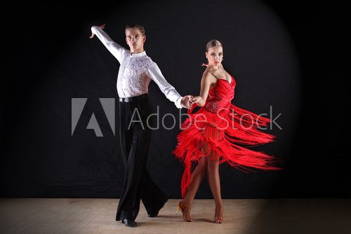 Latino dancers in ballroom against on black  Fototapety do Szkoły Tańca Fototapeta
