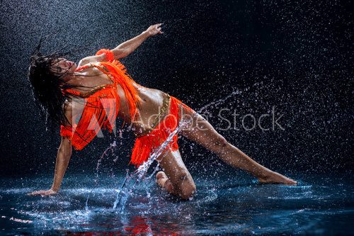 Woman dancing under rain in orange dress. Studio  Fototapety do Szkoły Tańca Fototapeta