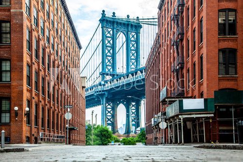 Manhattan Bridge between Manhattan and Brooklyn over East River seen from a narrow alley enclosed by two brick buildings on a sunny day in Washington street in Dumbo, Brooklyn, NYC Mosty Obraz