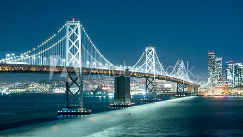 Oakland Bay Bridge and the city light at night. Mosty Obraz