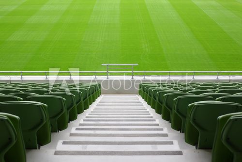 Rows of folded, green, plastic seats in very big, empty stadium  Stadion Fototapeta