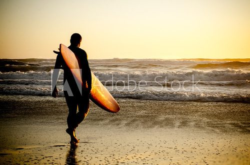 Surfer w blasku zachodzącego słońca nad oceanem Sport Fototapeta